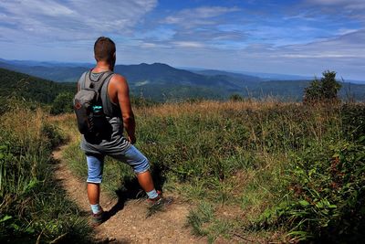 Rear view of man standing on land against sky