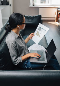 High angle view of woman using laptop while sitting on sofa at home