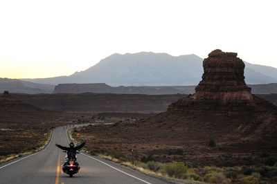 Rear view of man riding horse on mountain against clear sky