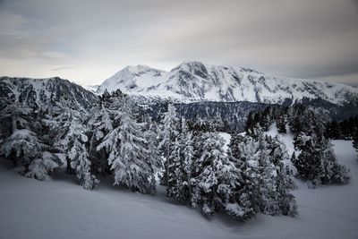 Scenic view of snow covered mountains against cloudy sky