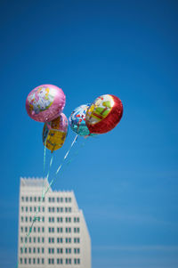 Low angle view of balloons against blue sky