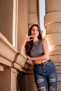 Portrait of young woman standing against wall