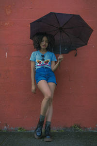 Portrait of teenage girl standing on umbrella during rainy season