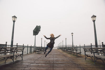 Young woman on pier against clear sky