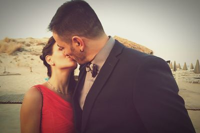 Close-up of couple kissing at beach against sky