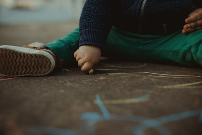 Low section of boy drawing on floor