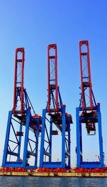 Low angle view of crane against clear blue sky