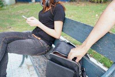 Midsection of man using mobile phone while sitting outdoors