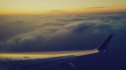 Close-up of airplane wing against sky during sunset