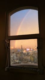 Buildings seen through wet glass window during sunset