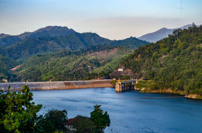 Scenic view of river by mountains against sky