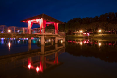 Reflection of illuminated bridge over river against sky at night