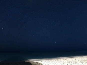 Scenic view of white sand beach against stars in sky at night