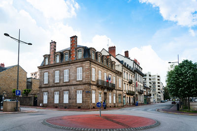 Road by buildings in city against sky