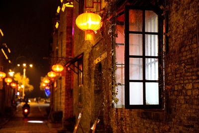 Illuminated street light by building at night