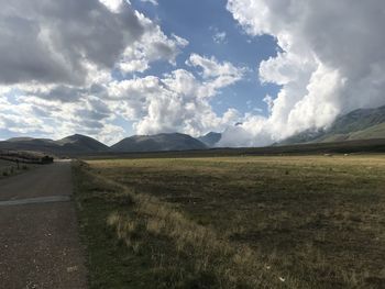 Scenic view of road by mountains against sky