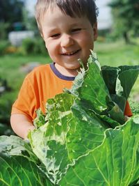 Portrait of a cute laughing boy holding a cabbage