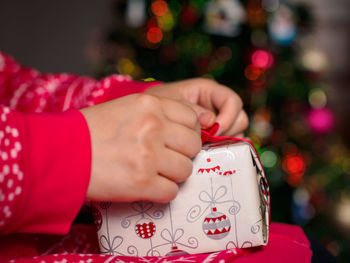 Cropped image of woman unwrapping gift during christmas