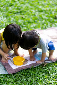 Children looking at container while crouching in public park