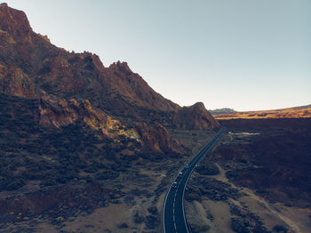 Road passing through mountain against clear sky