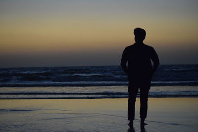 Rear view of silhouette man standing on beach