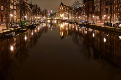 Reflection of illuminated bridge on river in city at night