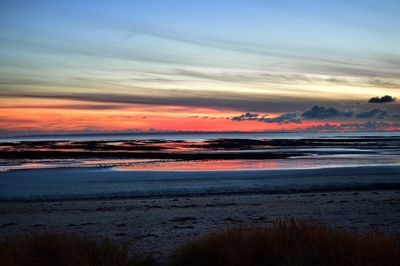 Scenic view of sea against dramatic sky during sunset