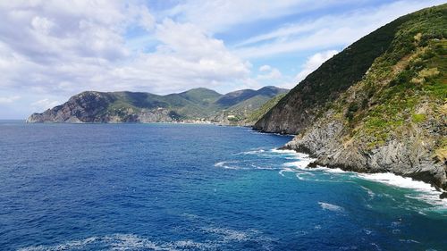 Scenic view of sea and mountains against blue sky