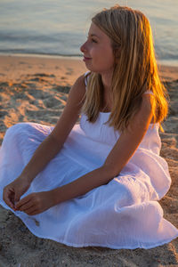 Young woman sitting on sand at beach