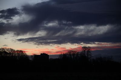 Silhouette of trees against cloudy sky