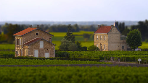 House on field by houses against sky