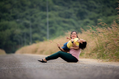 Full length of young woman sitting on road