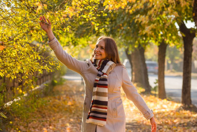 Side view of young woman standing against trees