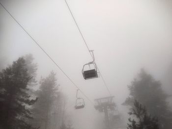 Low angle view of power lines in foggy weather