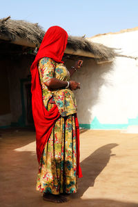 Side view of woman in traditional clothing standing outside house
