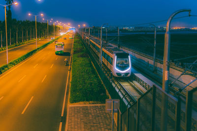 High angle view of train by vehicles on illuminated road at night