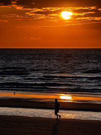 Silhouette people on beach against sky during sunset