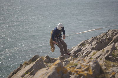 High angle view of man climbing on mountain against sea