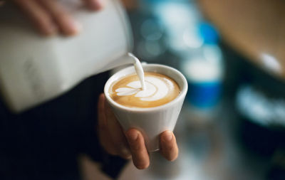 Close-up of hand pouring milk in coffee