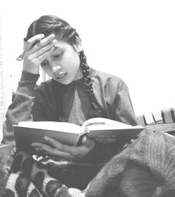 Portrait of young woman sitting on book