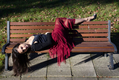 Woman lying on bench in park