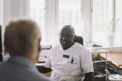 Mature male doctor advising patient during visit in clinic