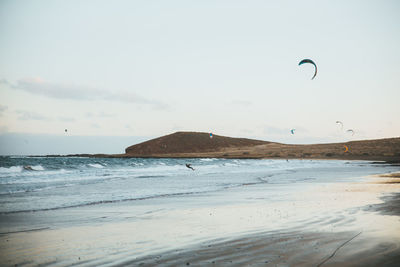 Person kiteboarding in sea against sky