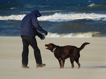 Full length of man with dog standing at beach