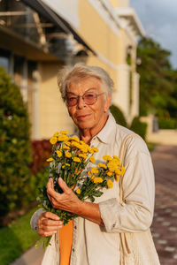 Portrait of elderly women holding yellow flowers