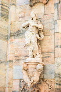 Low angle view of statue against brick wall