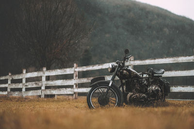 Abandoned motorcycle on field against trees