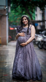 Portrait of young woman standing on footpath with her tummy out