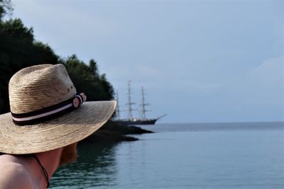 Rear view of woman in hat by sea against sky