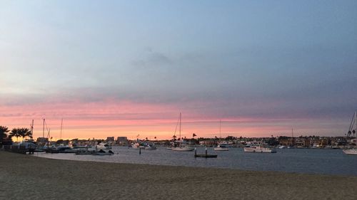 Boats moored in calm sea at sunset